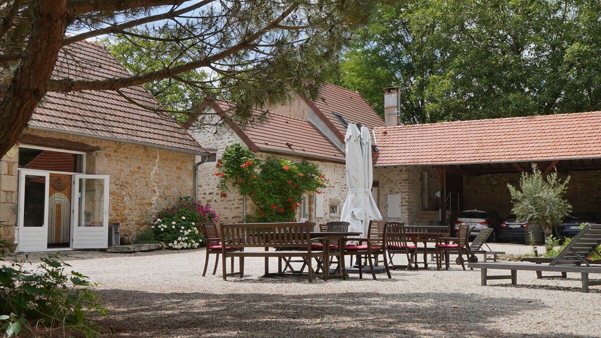 La cour du domaine, sa grande table commune et ses bâtiments en pierre.