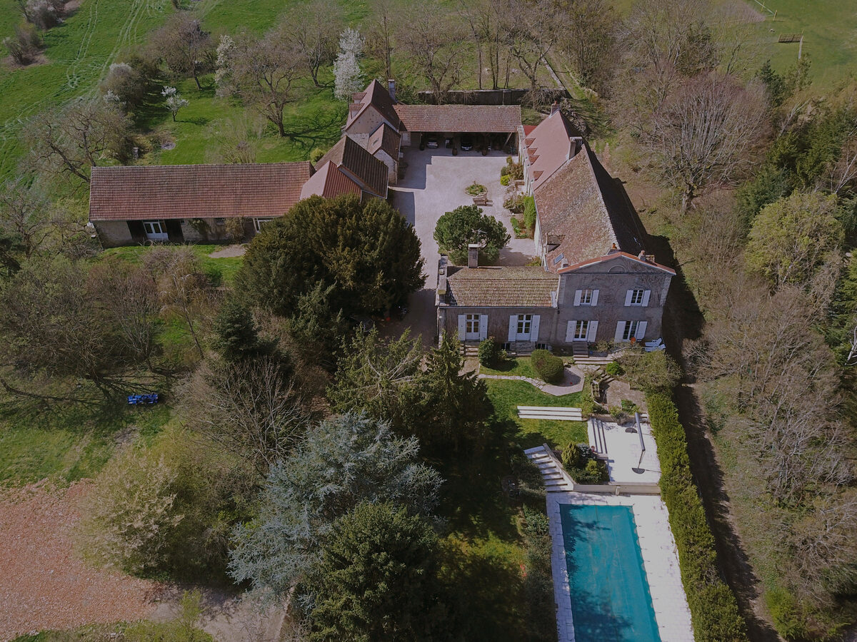 Le domaine vu du ciel : les bâtiments autour de la cour, le parc et la piscine.